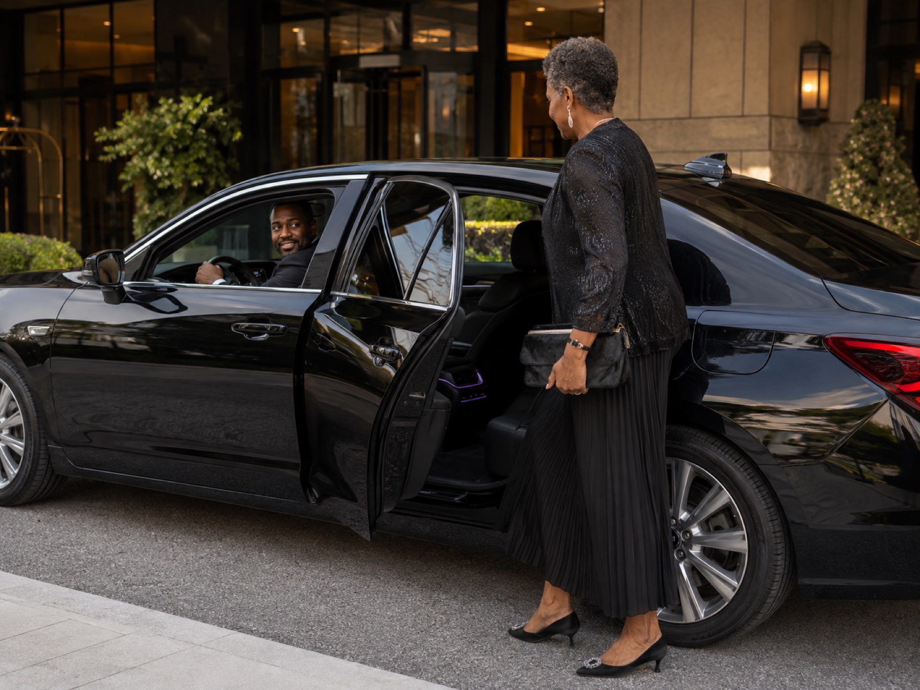 Ride passenger entering through the rear passenger door while her driver welcomes her
